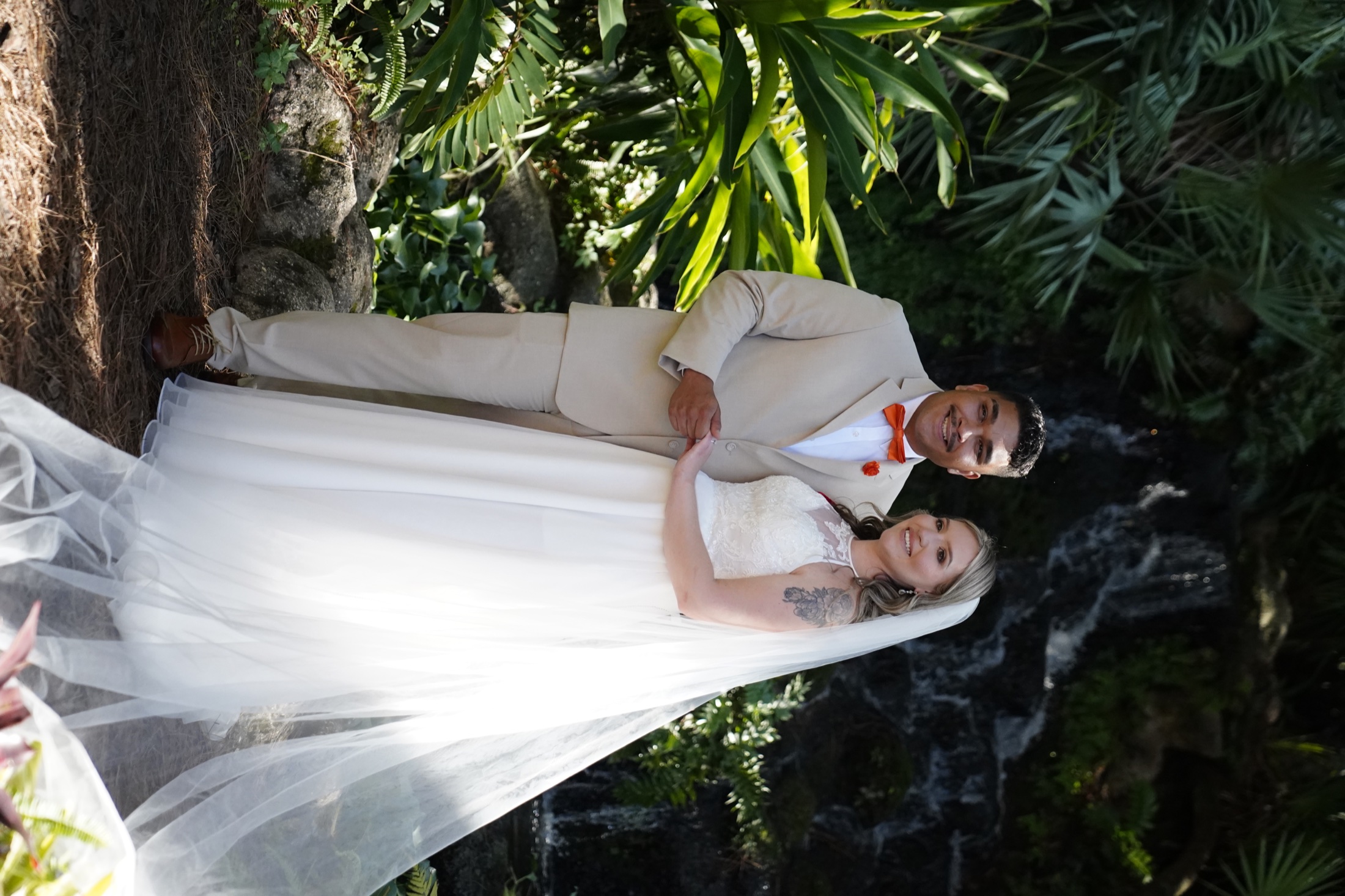 Bride and groom standing together near a waterfall