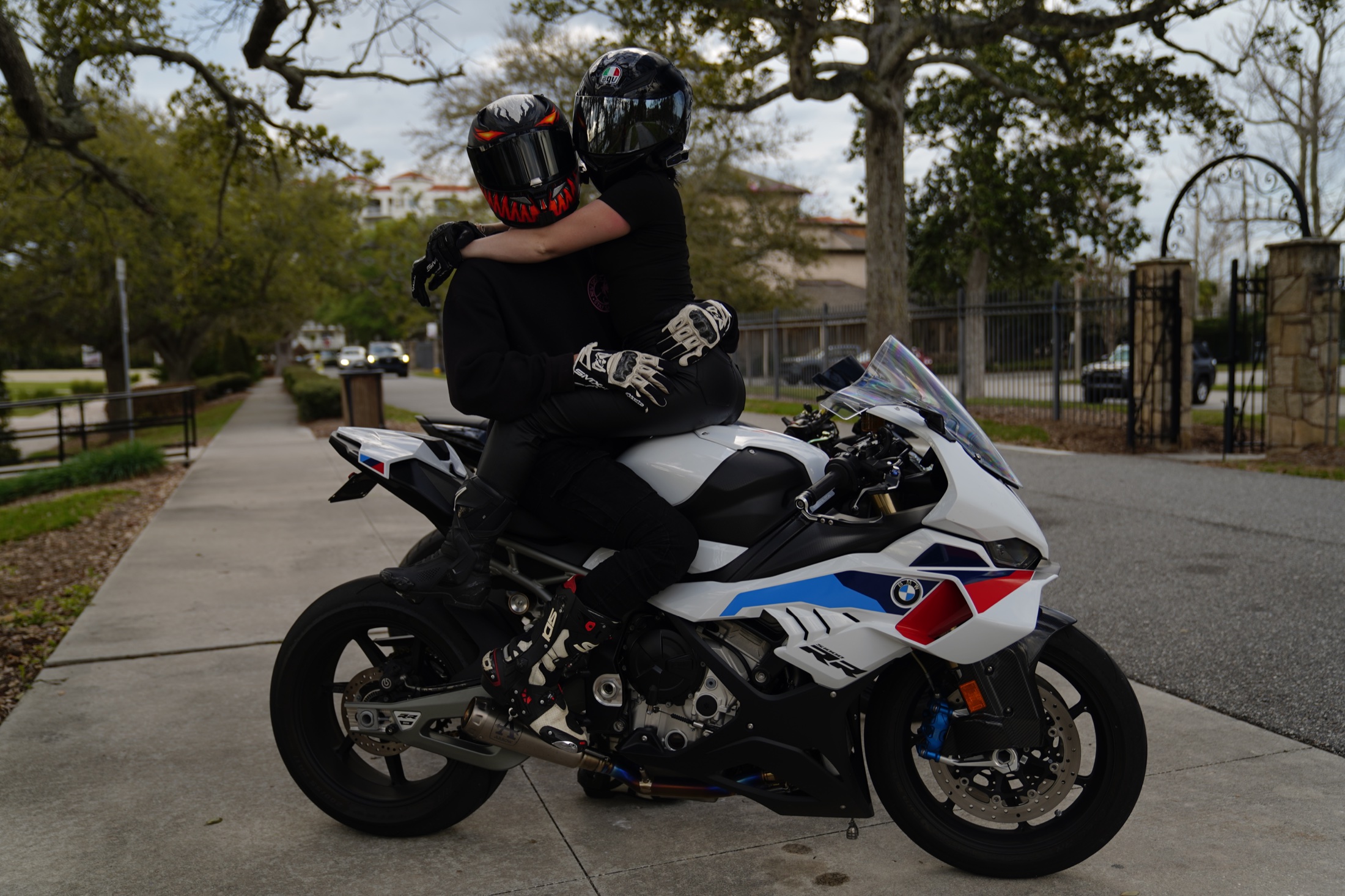 Two helmeted riders embracing on a white motorcycle