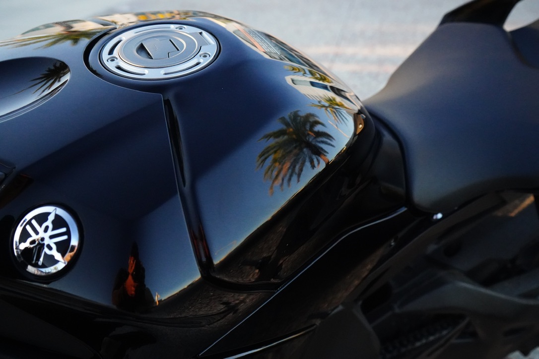 Close detail of a black Yamaha motorcycle tank reflecting palm trees