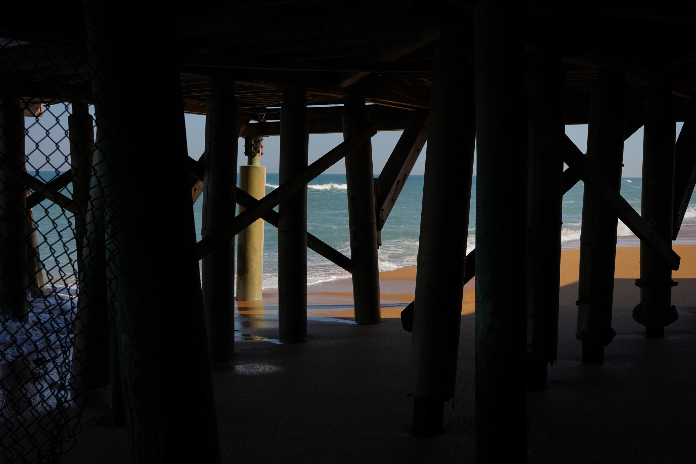 Ocean viewed through the structure beneath a pier
